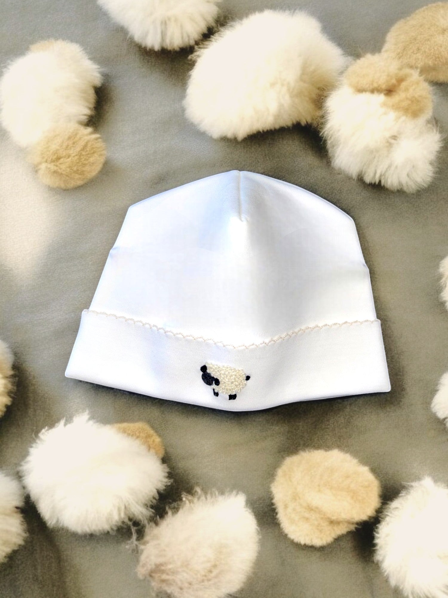 Gorro bebé algodón Pima blanco con bordado de oveja para recién nacido en fondo con pompones